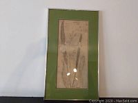 Full view of the batik art piece, showing floral motif in muted tones with silver frame and green mat