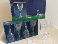 Four D'Arques Regina crystal stemware glasses in original blue and green box shown alongside the clear crystal three-candleholder on a white surface