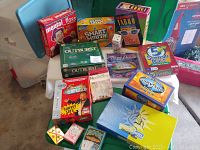 Photo showing board games including Mental Floss, Smart Mouth, Celebrity Taboo, Outburst, Trivial Pursuit, 5 Second Rule, Survivor, Family Feud DVD, Poetry Slam, and related accessories on table.