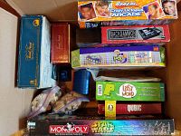 Top-down photo of packed box showing multiple boxed games including Backgammon, Octopus, Trivial Pursuit, Last Word and Qubic