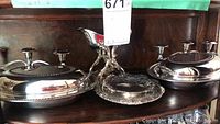 Overall view of the silverplate set including serving plates, small tray, gravy boat, and candle holders