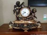 Front view of clock showing two cherubs and enamel dial