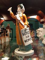 Front angle view showing figurine's posture and sign