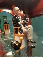 Front view of seated doctor figurine holding a small bottle
