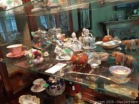Photo of glass shelf containing various porcelain and figurine items described by seller.