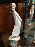 Front-left side view of the porcelain doctor figurine showing elongated body and face details including mustache and glasses.