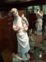 Front left angle view of the white porcelain doctor figurine holding a newborn baby.