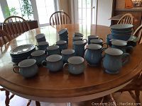 Full spread of dinnerware pieces on table, showing plates, bowls, mugs and ramekins.