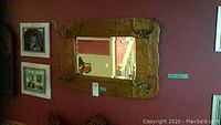 Full view of the vintage solid wood framed hall entry mirror mounted on the wall, showing four ornate metal coat hooks at each corner.