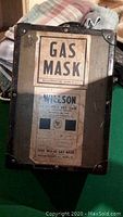 Front view of original metal and leather carry case with 'GAS MASK' and Willson Products branding labels.