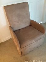 View of brown faux suede recliner chair from front showing cushioned seat, armrests, and backrest.