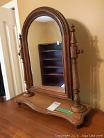 Front view of the antique dresser mirror showing the arched wood frame and base.