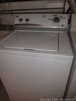 Front and side view of white Kenmore top-loading washing machine with closed lid and control panel visible