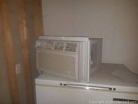 Side view of white Whirlpool window air conditioner on a white surface showing overall shape and size.