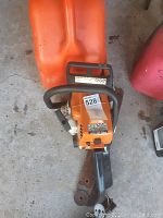 Full view of chainsaw body and orange gas can behind it