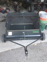 Full view photo of the black Yard Commander sweeper showing the body, wheels, and tow hitch attachment.