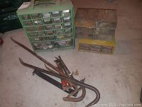 Metal pry bars and crow bars with three plastic hardware organizers behind them on concrete floor.