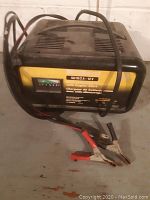 Front view of MotoMaster battery charger showing cables and clamps.