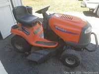 Full side profile of the orange lawn tractor with deck attached