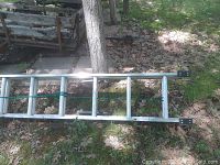 Close-up view of the top of the ladder, showing the construction of the rails, the black plastic end caps, and the green rope securing the sections together.