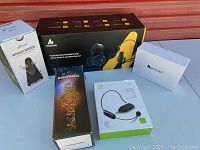 Photo showing the five boxed items: M-Audio microphone with headphones, Donner mechanical metronome, Shidu U8 wireless microphone, and two other boxed microphones.