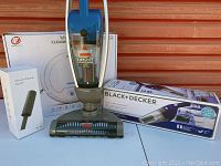 Bissell Lift-Off upright vacuum cleaner in front of its box and Black+Decker handheld vacuum box