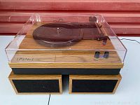 Vinyl record player with dust cover and two speakers beneath