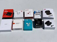 Photo showing 10 different boxes of wireless earbuds including MPOW M9, i7-Mini, Bluetooth Q25, SoundLiberty S3, AUKEY, Predator, XY-7, i11 models in varied packaging styles and colors.