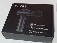Closed box of Flyby deep tissue massage gun showing product image and features: 3 impact modes, 4+ hours charge, 6 massage heads.
