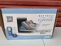 Front view of Mattress Genie box showing product brand, image of inflatable bed support wedge with remote, and main features including up to 26 inch lift.