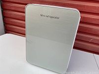 Front view of compact mini refrigerator cooler box with silver front panel labeled 'Mini refrigerator'.