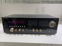 Front view of the black glossy Technical Pro RX51Uri amplifier showing tone control sliders, input selection buttons, power switch, and volume knob.