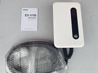 Top-down view of charging station, wrapped cable and user manual