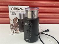 Yessvic coffee grinder with its product box, showing black cylindrical design with control dial and clear lid.