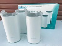 Three white cylindrical TP-Link Deco units in front of original retail box