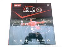 Box of Syma X8HG drone showing branding and key features such as HD camera, headless mode, altitude hold, and 3D flips.