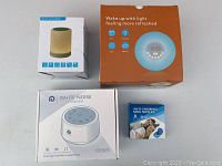 Lot items in boxes including a touch sound lamp, light alarm clock, white noise sound machine, and anti-snoring mouthpiece.