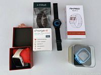 All five watches displayed with packaging and box; includes Fitbit Charge HR, Akaso Neon II, black watch, white watch in box, blue watch in clear box.
