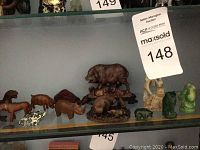 Shelf with multiple wooden and stone figurines including animals and Buddhas