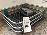 Modern gray plastic dish drainer with multiple plate slots and a utensil holder placed on a kitchen countertop.