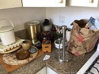 Kitchen countertop with pizza stone, cutting board, ice trays, timer, antique grinder, jars, vase and Magic Bullet blender base