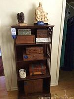 Bookshelf holding 8 ornate storage boxes and 2 statues on top