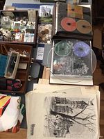 Top-down wide view showing assorted items arranged on a table including coins, CDs, postcards, and the cartoon duvet cover.