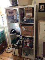 Front and side view of white IKEA cubby shelves filled with various boxes and items to depict size and compartment layout.