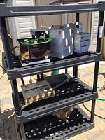 Plastic shelving unit holding various boxes and cleaning products, showing three tiers with lattice-style shelves and vertical poles.