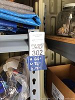 Close-up photo showing the shelving unit's dimensions labeled 60" height, 36" width, and 19" depth on a blue tag attached to the metal frame.