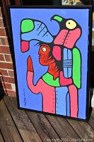 Full front view of framed painting leaning against brick wall outdoors.