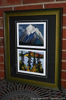 Full view of framed double prints resting against brick wall