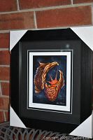 Framed and matted fine art print titled "Sun is Life" by Don Chase, resting against a brick wall with protective corner covers on frame.