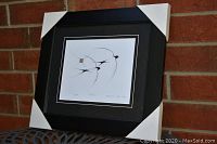 Framed "Swallows" print by Benjamin Chee Chee with protective corner guards leaning against a brick wall.